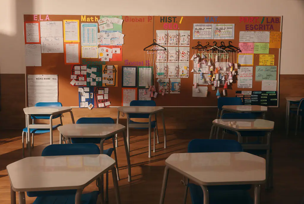 Sala de aula com carteiras e mural de trabalhos dos alunos em inglês e português