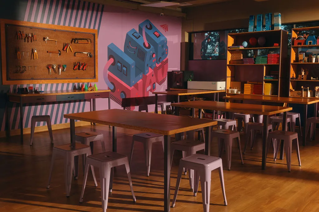 Laboratório maker com mesas, banquinhos, painel de ferramentas e estantes de materiais